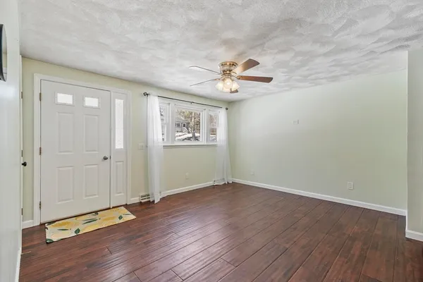 a view of an empty room with a window and wooden floor