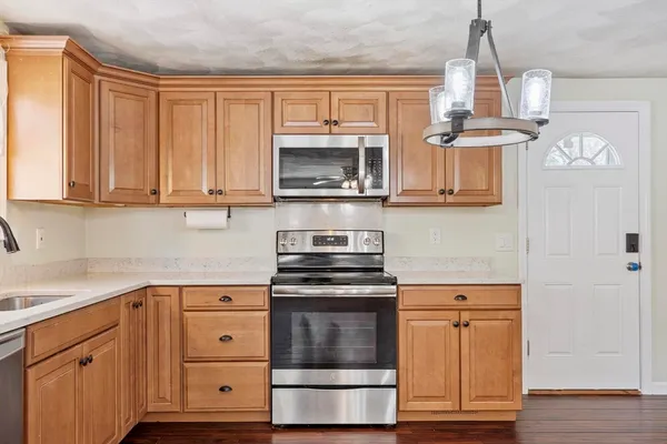 a kitchen with cabinets stainless steel appliances and a wooden floor
