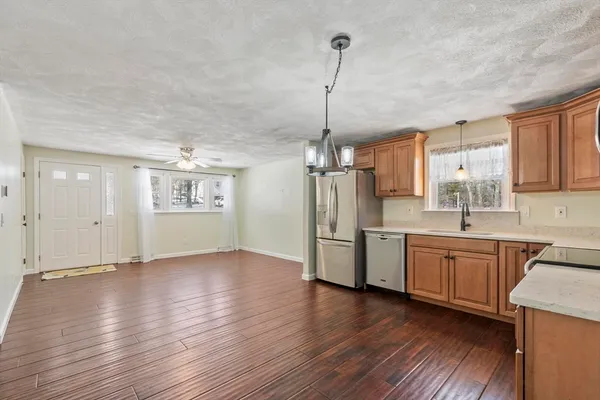 a kitchen with stainless steel appliances granite countertop a refrigerator a sink dishwasher a stove and white countertops with wooden floor