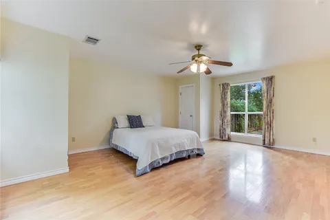 a spacious bedroom with a large bed chandelier and a window
