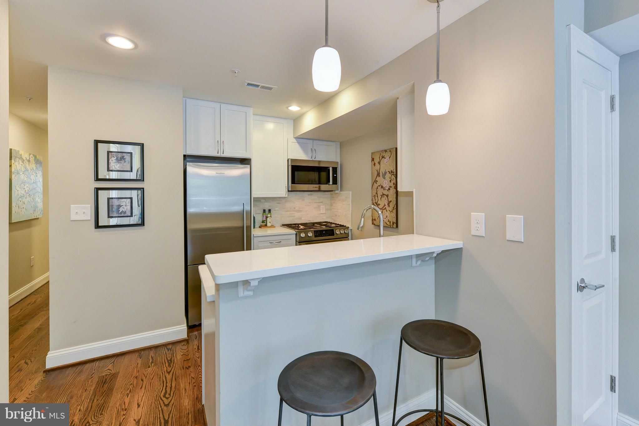 1823 S Street Northwest, Unit 3 Washington, DC 20009 - Photo 9 of 24 a kitchen with stainless steel appliances granite countertop a refrigerator a sink dishwasher a stove and a microwave with wooden floor