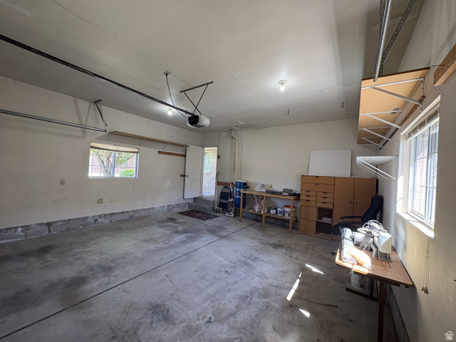 486 West 120 North Orem, UT 84057 - Photo 30 of 30 Spacious garage featuring a concrete floor, two windows providing natural light, overhead lighting fixtures, and an automatic garage door opener