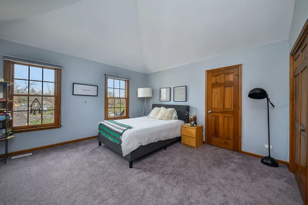 a spacious bedroom with a bed and wooden floor