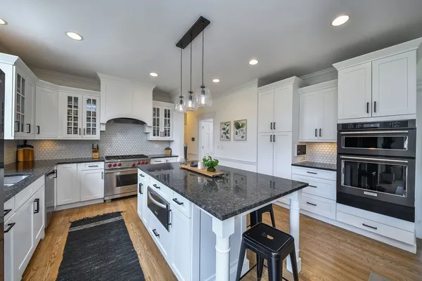 a kitchen with stainless steel appliances a stove a sink a microwave a center island and furniture