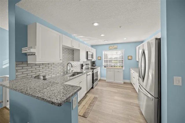 a kitchen with stainless steel appliances granite countertop a refrigerator and a sink