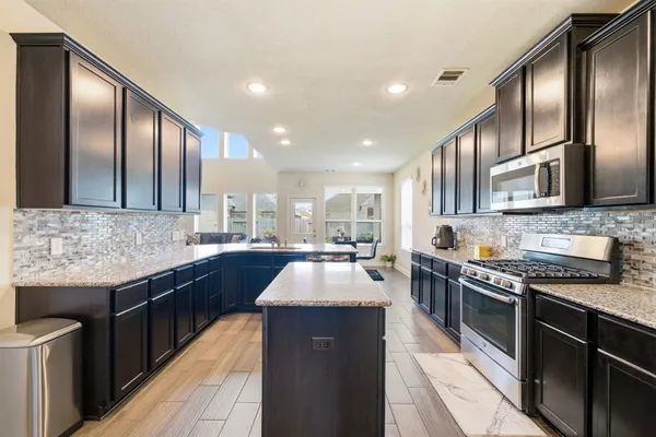 a large kitchen with granite countertop stainless steel appliances and wooden cabinets
