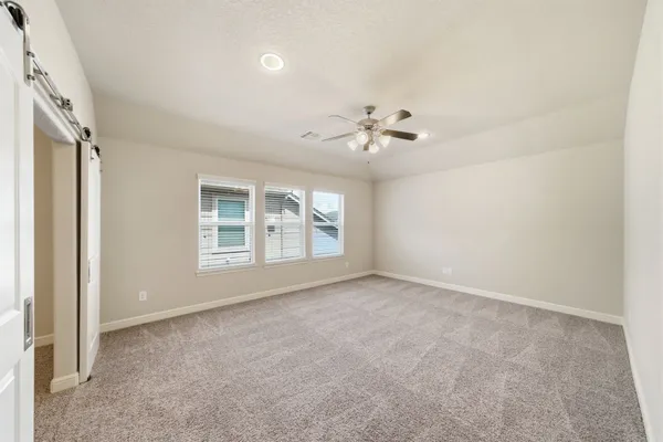 an empty room with windows and chandelier fan