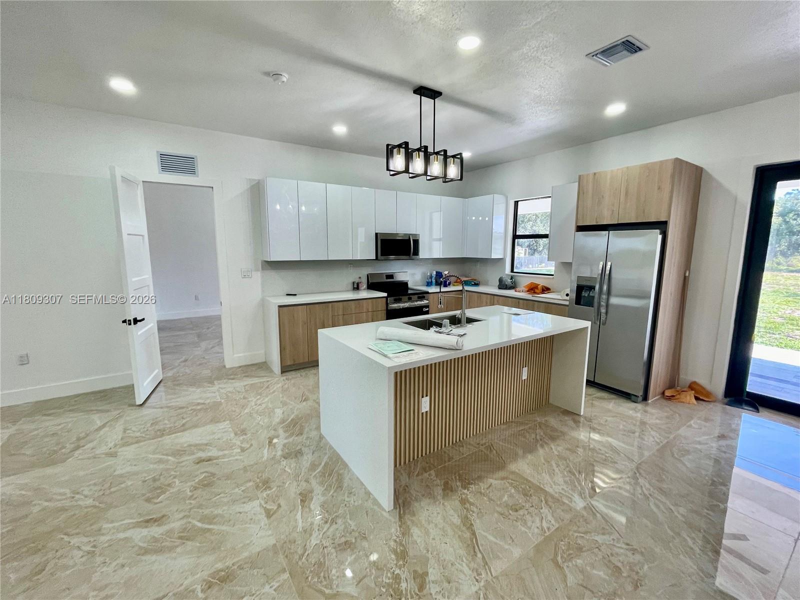 a large kitchen with stainless steel appliances a stove a sink dishwasher a refrigerator and a stove