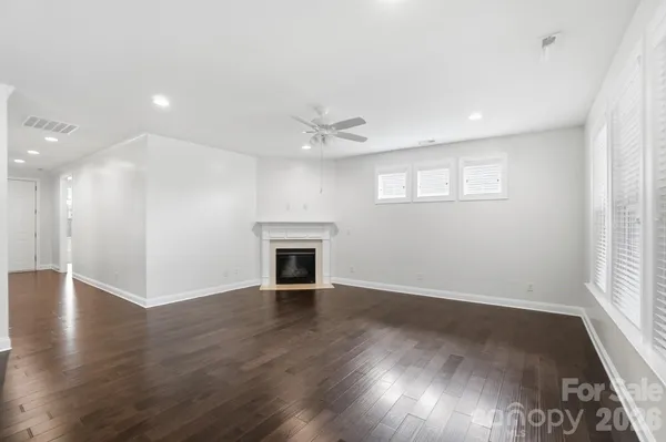 an empty room with wooden floor chandelier and windows