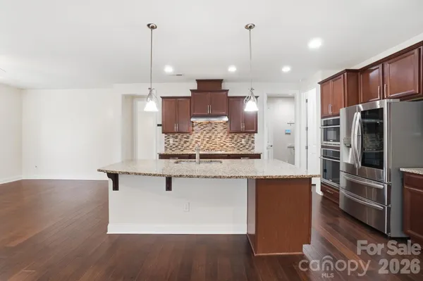 a view of kitchen with stainless steel appliances granite countertop cabinets and wooden floor