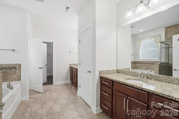 a bathroom with a granite countertop sink a mirror and a shower