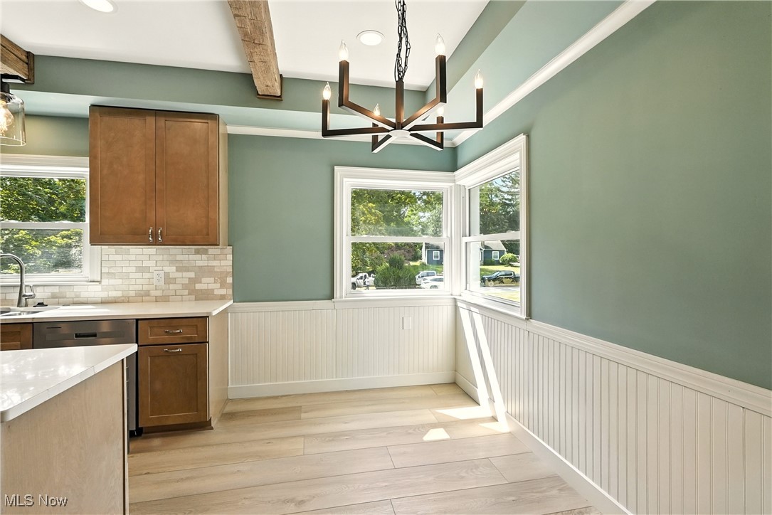 2844 Kent Road Stow, OH 44224 - Photo 13 of 47 Kitchen featuring brown cabinetry, light countertops, hanging light fixtures, a chandelier, and wainscoting