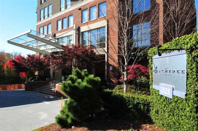 a front view of a multi story residential apartment building with yard and sign board