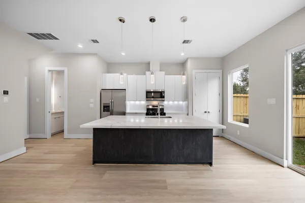 a view of kitchen with kitchen island a sink wooden floor and living room view
