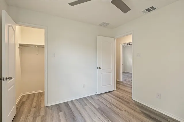 a view of empty room with wooden floor and fan