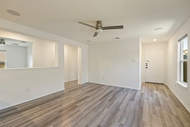 a view of an empty room with wooden floor and a window