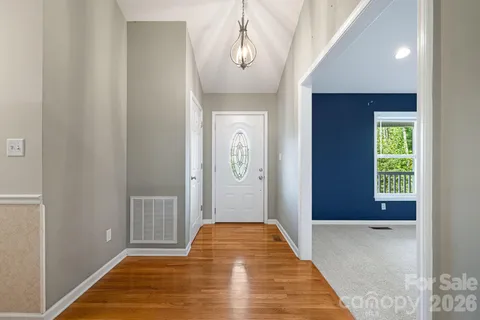 a view of a hallway with wooden floor and a livingroom