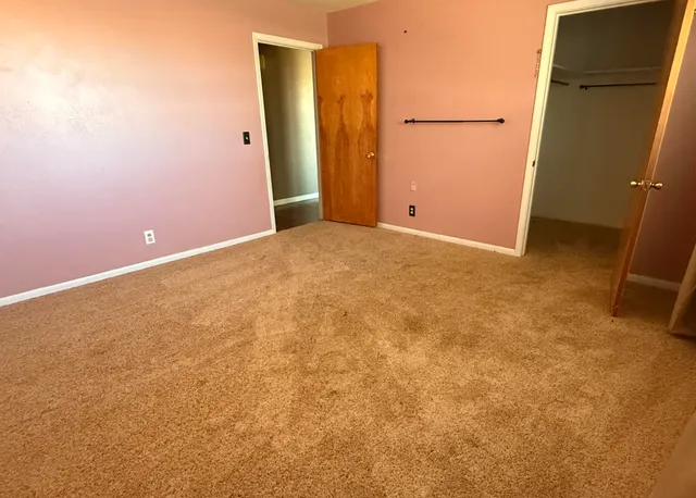 an empty room with windows and ceiling fan