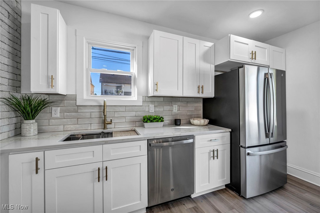 2128 Hampstead Road Cleveland Heights, OH 44118 - Photo 5 of 32 Kitchen with white cabinetry, stainless steel appliances, light stone counters, and backsplash