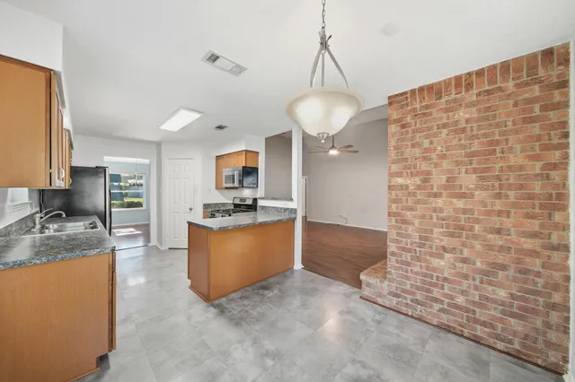 a large kitchen with kitchen island a sink stainless steel appliances and a chandelier