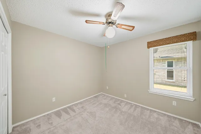 an empty room with a window and a fan
