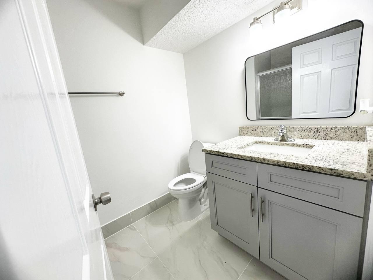 1033 Goldenrod Road Wellington, FL 33414 - Photo 5 of 8 a bathroom with a granite countertop sink toilet and mirror