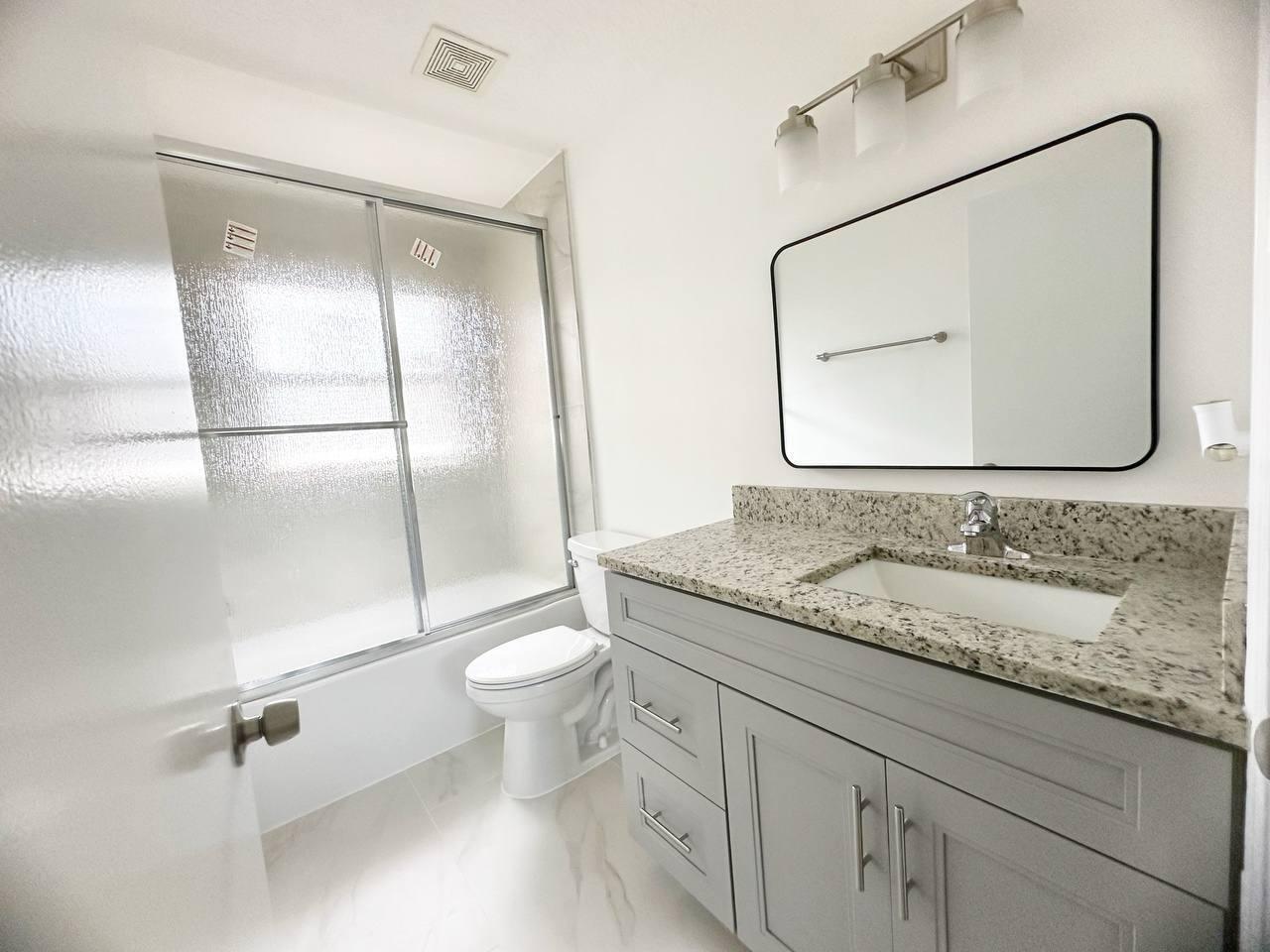 1033 Goldenrod Road Wellington, FL 33414 - Photo 8 of 8 a bathroom with a granite countertop sink a toilet and a mirror