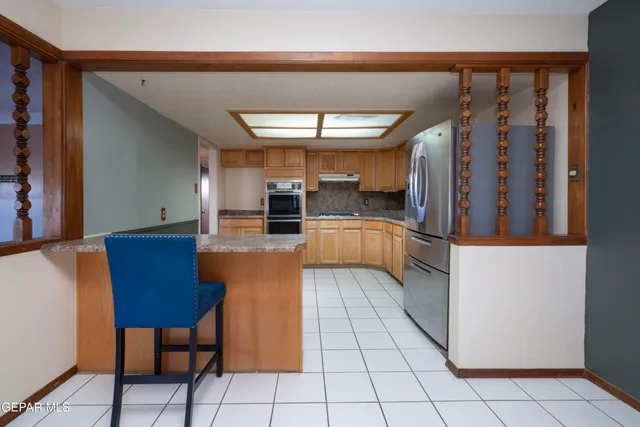 a kitchen with stainless steel appliances kitchen island granite countertop a table and a chair