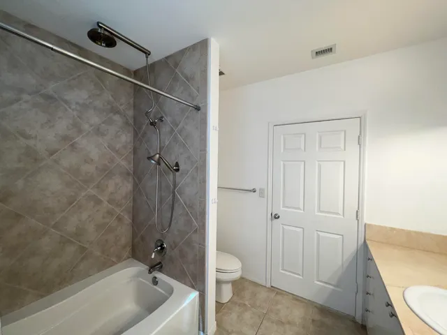 a bathroom with a granite countertop sink a toilet and shower