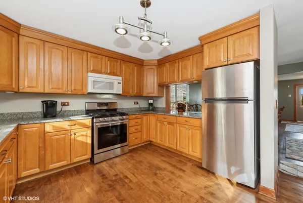 a kitchen with stainless steel appliances granite countertop a refrigerator a stove top oven a sink and dishwasher