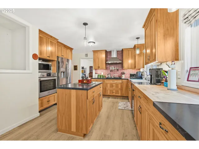 a kitchen with stainless steel appliances granite countertop a sink refrigerator and cabinets