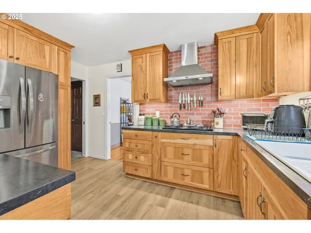 a kitchen with stainless steel appliances granite countertop a refrigerator a sink dishwasher and wooden cabinets with a large window