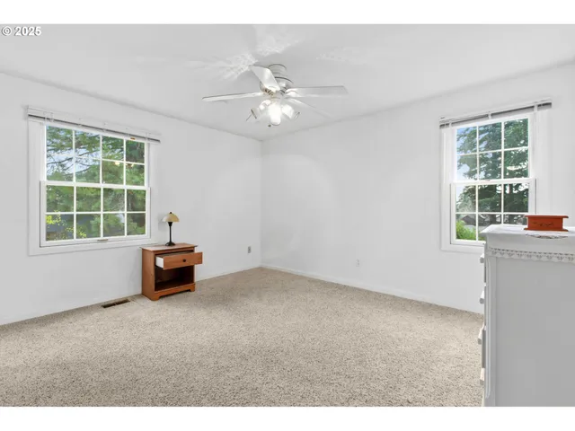 an empty room with windows and chandelier fan