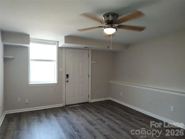 an empty room with wooden floor fan and windows