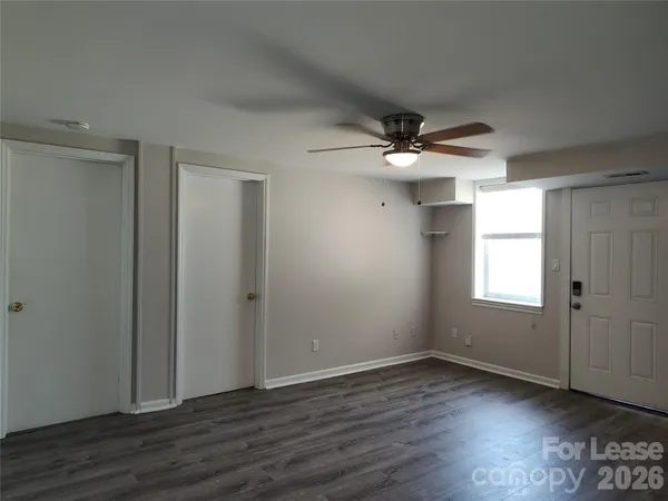 an empty room with wooden floor and ceiling fan