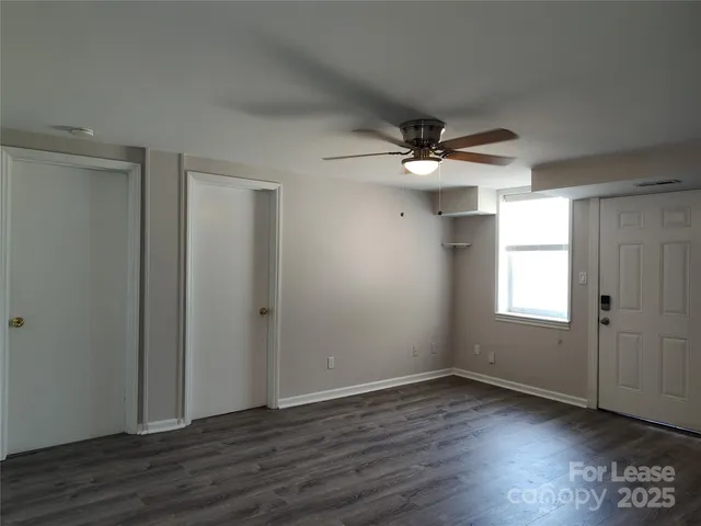 an empty room with wooden floor and ceiling fan