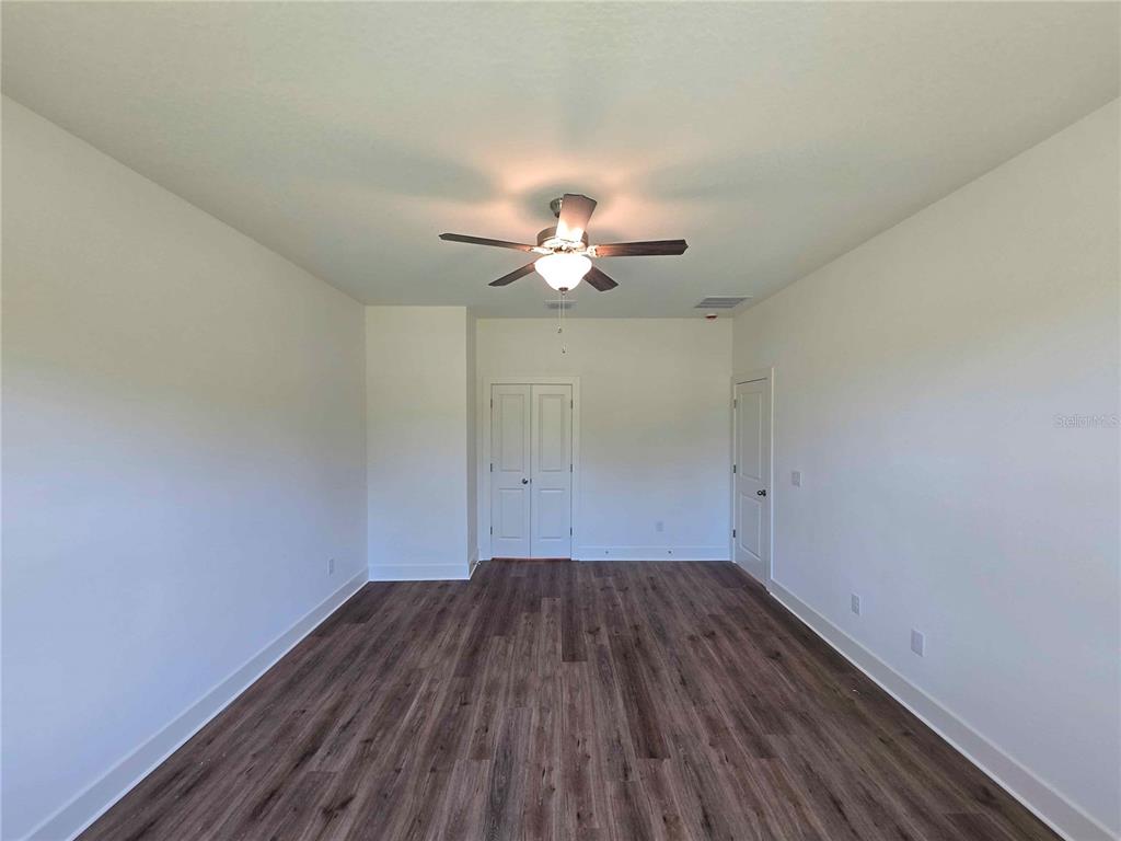 3352 Daybreak Run Loop Spring Hill, FL 34609 - Photo 7 of 15 a view of a room with wooden floor and a ceiling fan