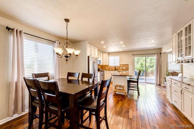 2016 West Ashwood Place Highlands Ranch, CO 80129 - Photo 13 of 40 a dining room with wooden floor a chandelier a wooden table and chairs