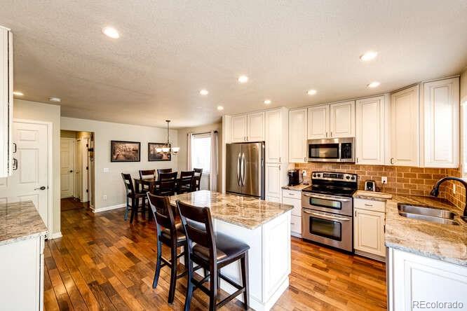 2016 West Ashwood Place Highlands Ranch, CO 80129 - Photo 10 of 40 a kitchen with stainless steel appliances kitchen island granite countertop a stove top oven a sink a stove a dining table and chairs