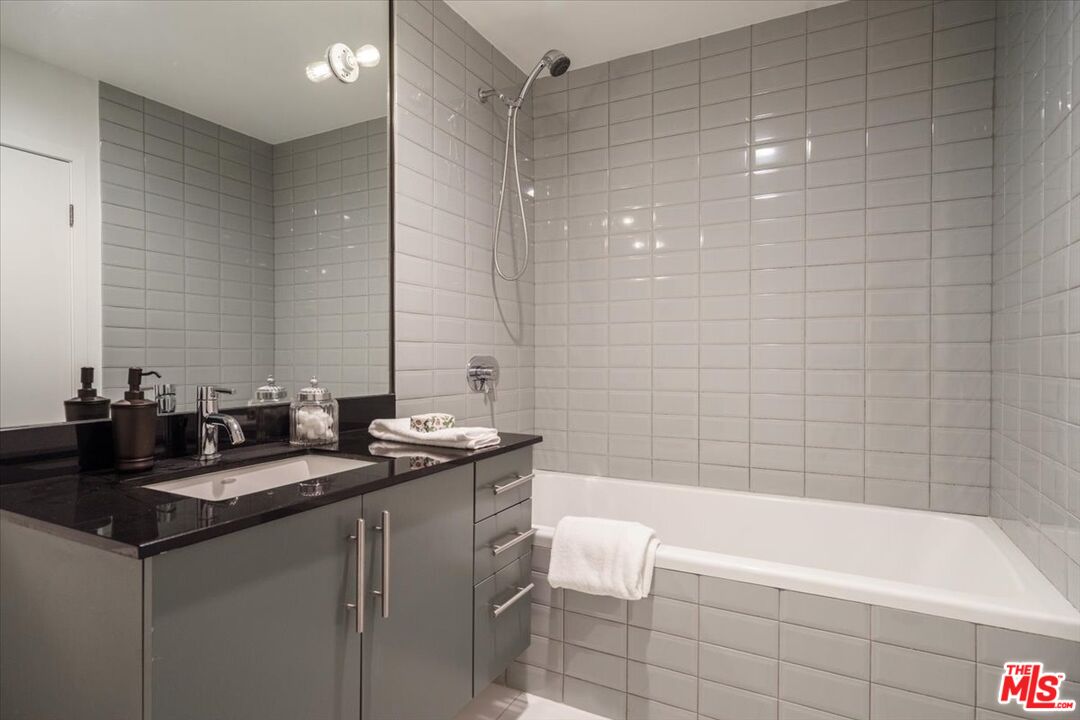 510 South Hewitt Street, Unit 106 Los Angeles, CA 90013 - Photo 16 of 26 a bathroom with a granite countertop sink a mirror a bathtub and shower