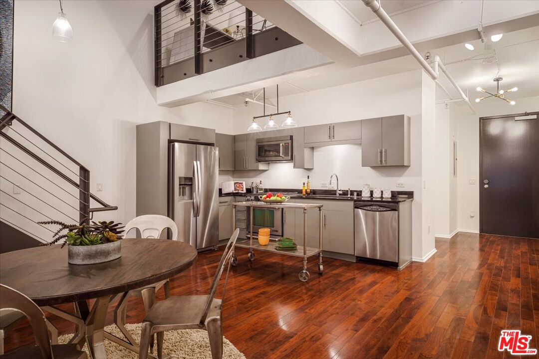 510 South Hewitt Street, Unit 106 Los Angeles, CA 90013 - Photo 3 of 26 a kitchen with a table chairs refrigerator and microwave
