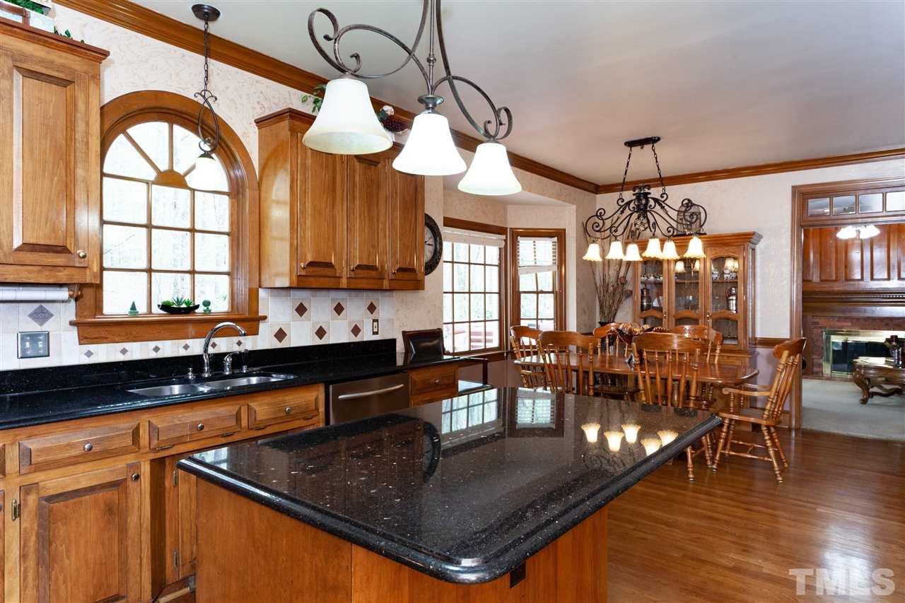 701 Presnell Court Raleigh, NC 27615 - Photo 8 of 24 a kitchen with stainless steel appliances granite countertop a stove a sink a dining table and chairs with wooden floor