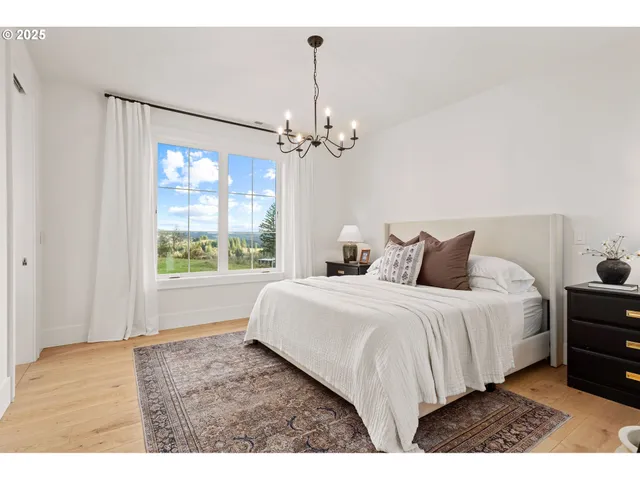 a spacious bedroom with a bed a chandelier and a window