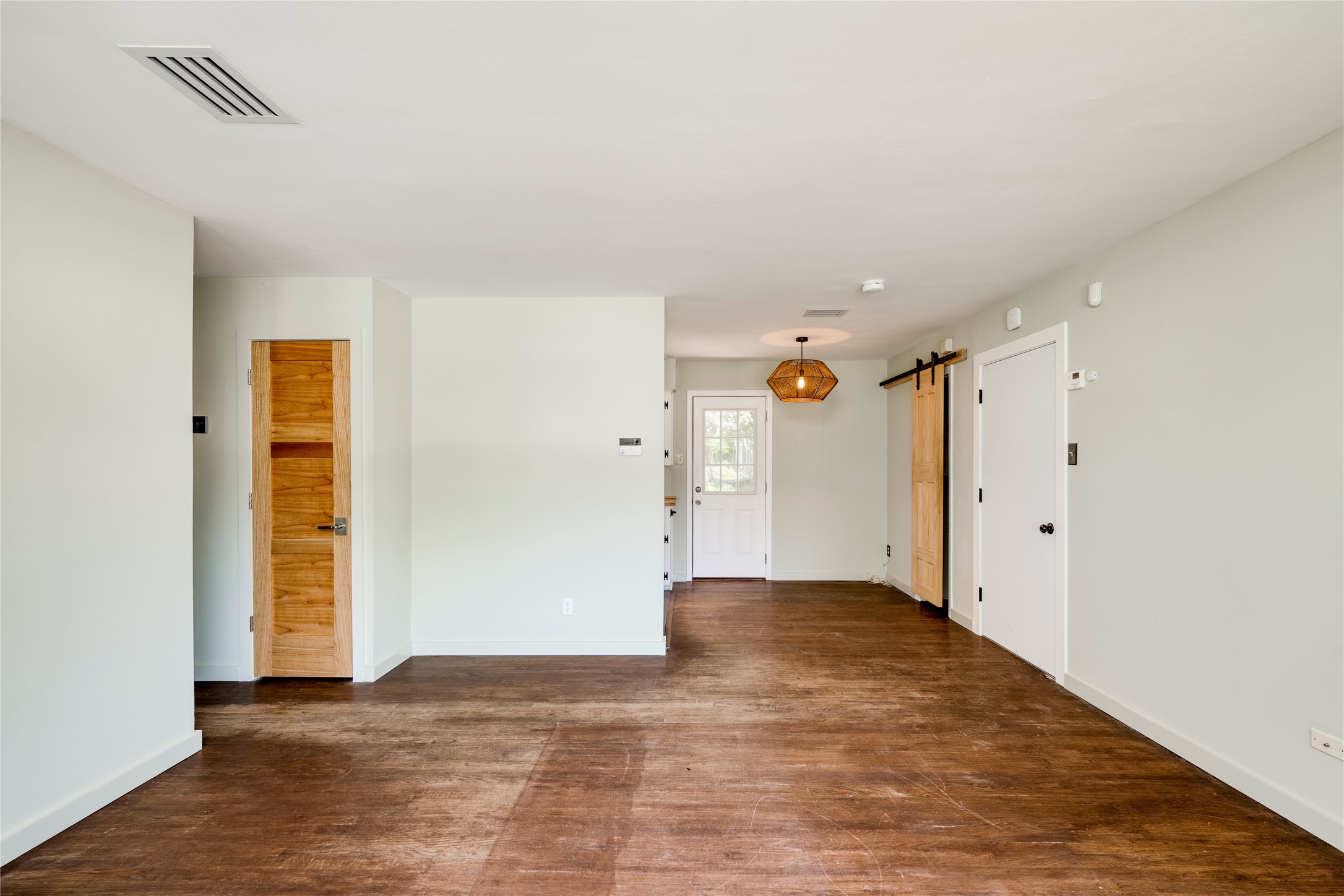 1707 Overhill Drive Austin, TX 78721 - Photo 5 of 36 Wood flooring and modern barn doors distinguish this open-concept interior space.