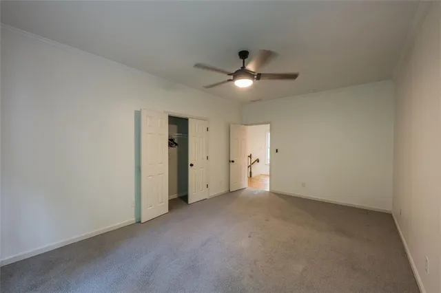 an empty room with a ceiling fan and closet area