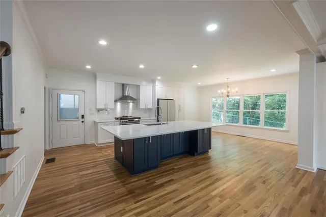 a large kitchen with stainless steel appliances granite countertop a large counter top a sink and a wooden floors