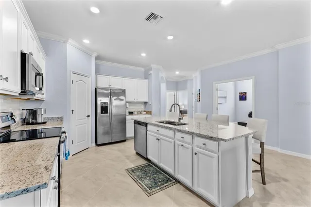 a kitchen with stainless steel appliances granite countertop a sink stove refrigerator and cabinets