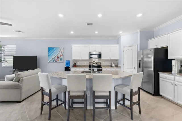 a kitchen with stainless steel appliances granite countertop a refrigerator a stove a sink and white cabinets