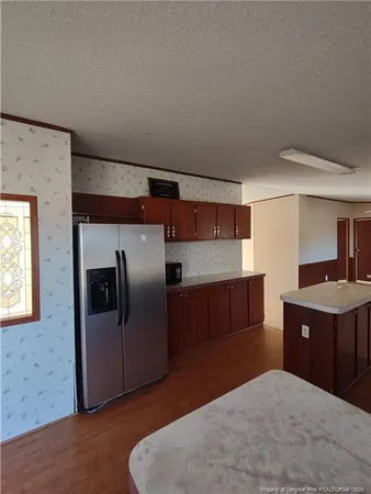 a kitchen with stainless steel appliances kitchen island granite countertop a refrigerator and a stove top oven