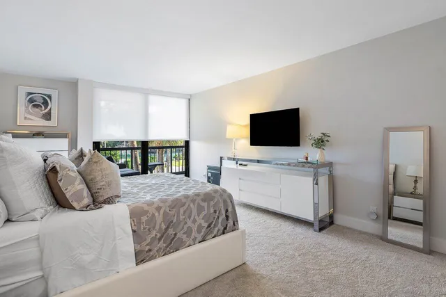 a bedroom with a bed table and flat screen tv